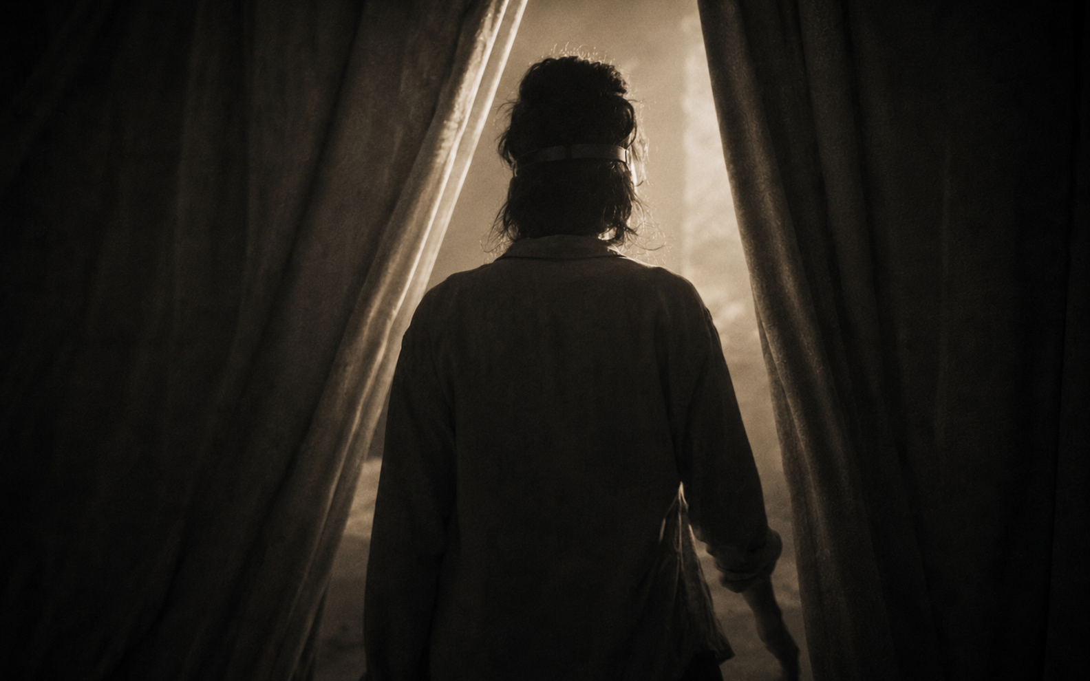 An anonymous blindfolded participant stepping through a curtain